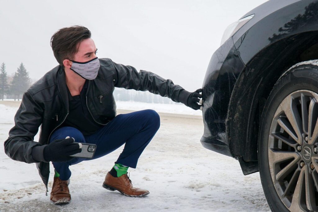 Man looking at front bumper of a car, evaluating the value